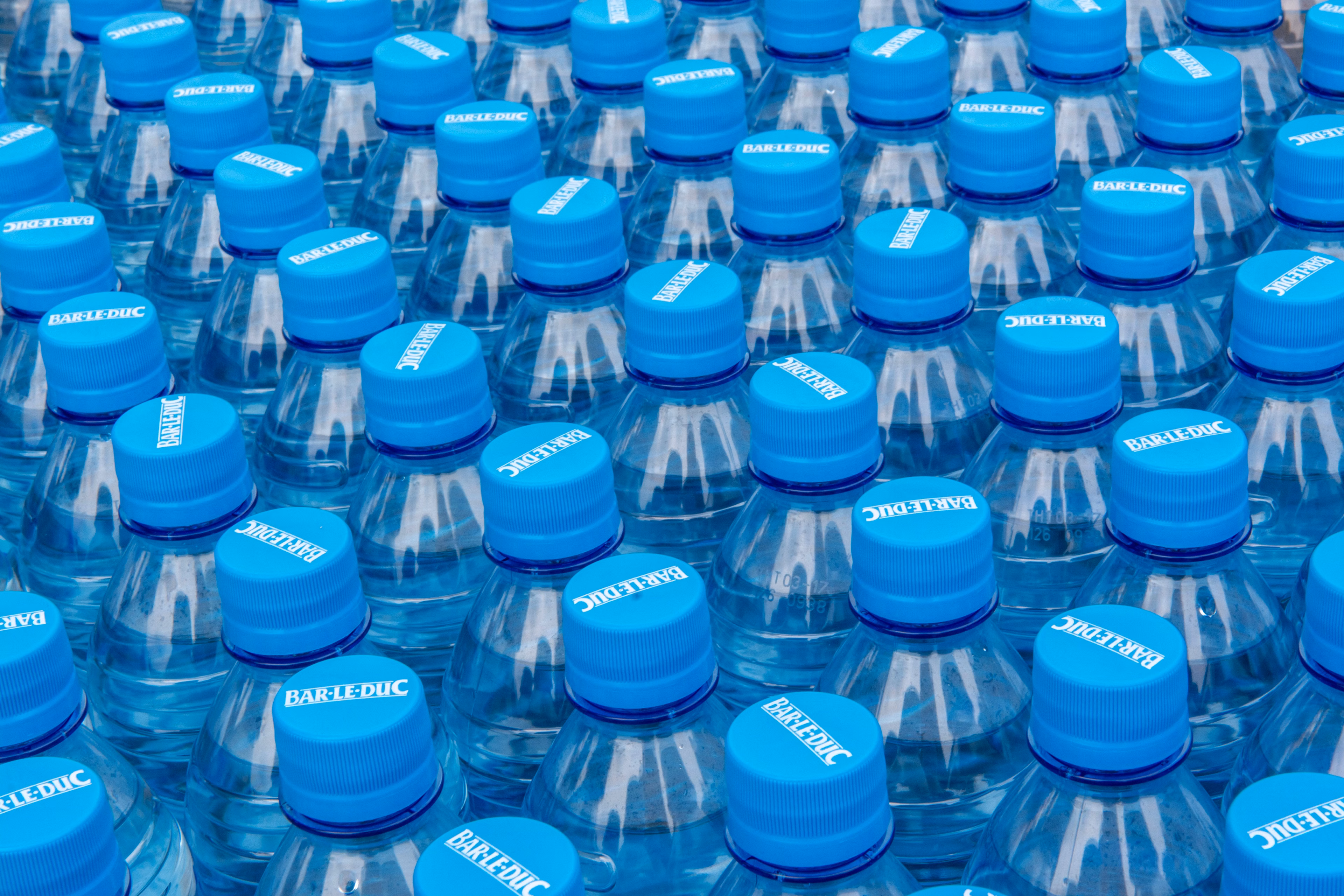 Staplade plastflaskor med vatten och blå kapsyler